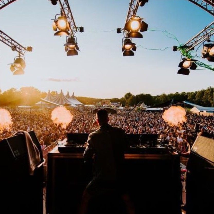 View from behind the DJ booth over a festival crowd